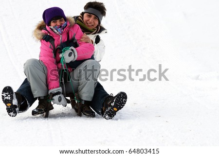boy and girl having fun in the snow, sledging.