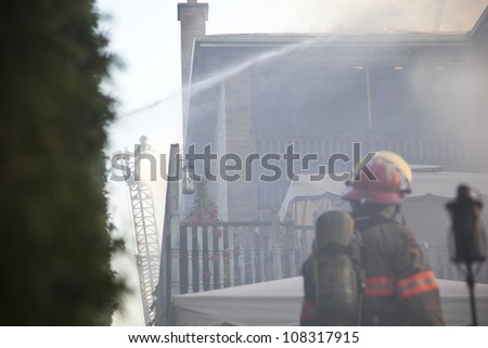 BRAMPTON, ONTARIO -  JULY 20 2012 - Firefighter watches fellow firefighters attempting to douse a house fire burning at 20 Esker Drive in Brampton Ontario on July 20, 2012