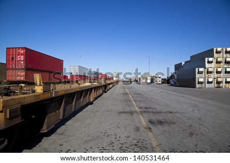 Rail yard with containers loaded onto train with flat deck trucks