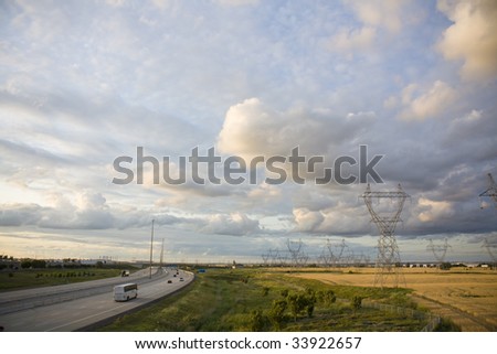 Power lines in yellow field next to highway