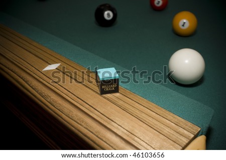 Close up shot of billiard chalk on pool table with balls in background