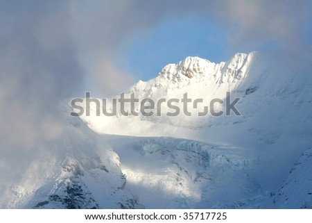 Sun light break through the clouds and projects on the snow covered mountain near Jungfrau in Switzerland