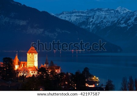 Spize castle and lake Thun background with snow covered Alps mountains night view in Switzerland