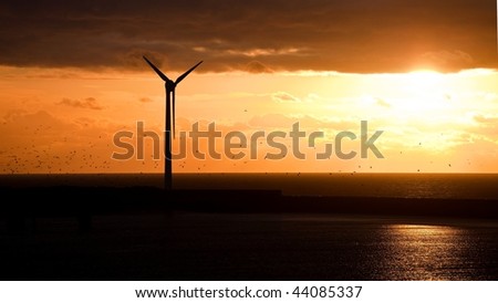 A wind turbine in the sea under sunset