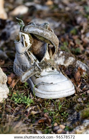 Old, discarded children\'s shoe in a field