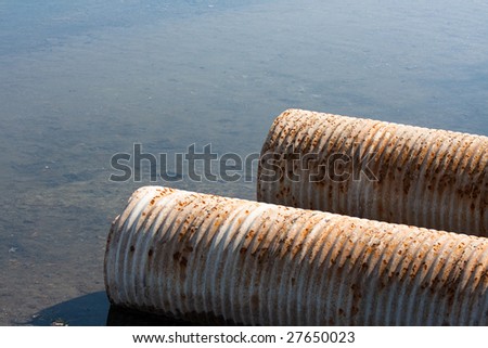 Rusty drainage pipes emptying into a river.