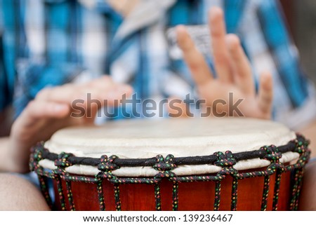 Young man playing on djembe. Shallow depth of field for emphasis on a musical instrument