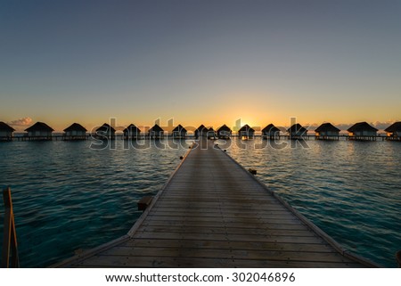 sunset moment at luxury resort, wooden walkway to water villa bungalow, Maldives