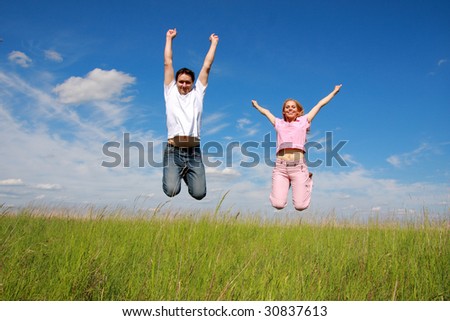 Two young people, jumping, blue sky, and green grass, Man and woman.