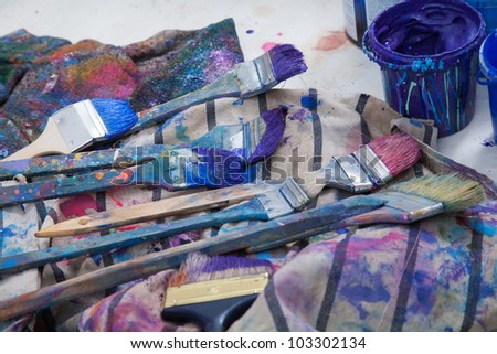 Paintbrushes covered with paint lying on a rag next to the jar of paint in a painter\'s studio