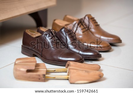Two pairs of brown handmade classic men\'s shoes  with a shoe pads and stretchers inside and beside the shoes