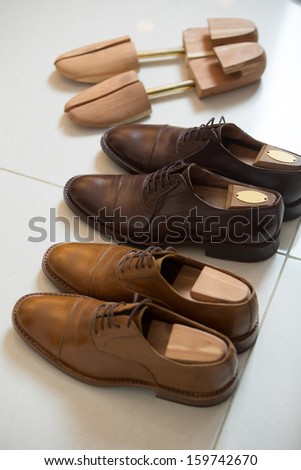 Two pairs of brown handmade classic men's shoes  with a shoe pads and stretchers inside and beside the shoes