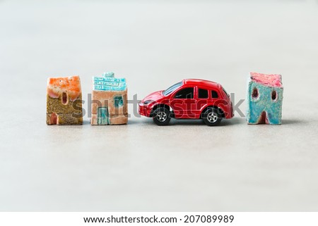 Three toy ceramic houses and toy red car  between them