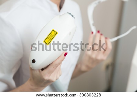 Cosmetician holding laser device ready for  laser therapy cosmetology procedure