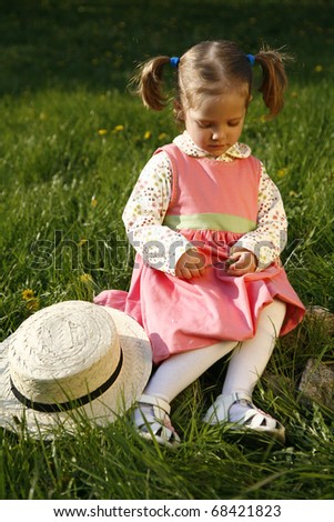 Upset little girl with her eyes down with a straw hat off and a flower in her hands