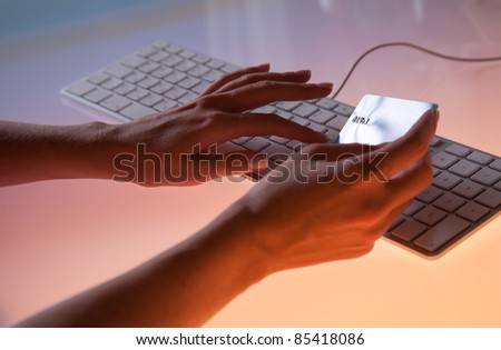 Woman's right hand holding a credit card above a keyboard getting ready to enter data