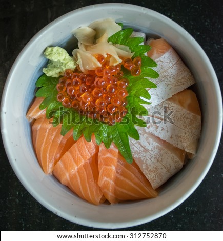 Salmon Ikura Don with wasabi and ginger or salmon rice bowl on the black table, Japanese food