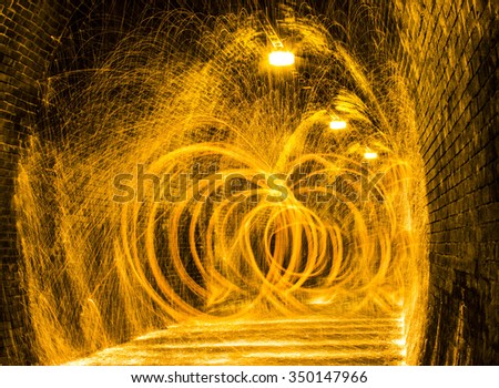 Steel wool burning and spinning in a tunnel making yellow sparks and rings of fire