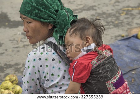 HA GIANG, VIETNAM - SEPTEMBER 19: Baby sleep on his mother\'s back  in the market Dong van, Vietnam
