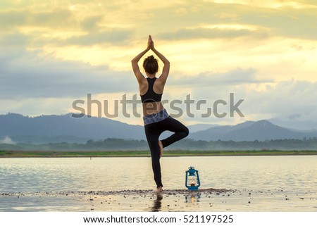 Asian Young woman doing yoga in morning park,Woman Yoga relax in nature,Asian woman is practicing yoga at mountain lake,silhouette yoga,yoga relax