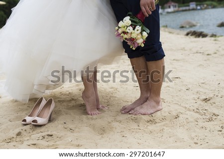 and bouquet in hands and shoes on the sand