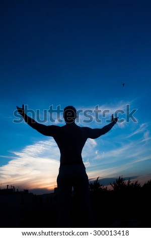 Man on top.  Conceptual design. Concept of abstract  man with open arms facing a city's silhouette at the sunset