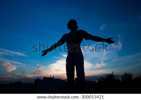 Man on top.  Conceptual design. Concept of abstract  man with open arms facing a city\'s silhouette at the sunset