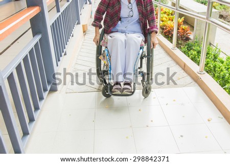Handicapped woman on wheelchair go to the building using ramp for disabled