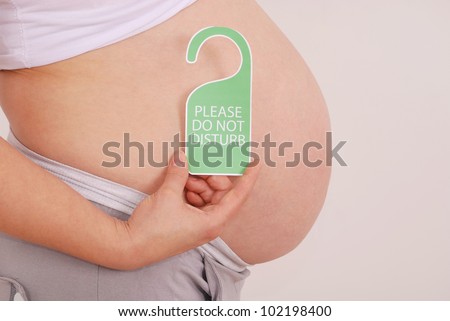 Do Not Disturb sign in his hands pregnant woman on grey background