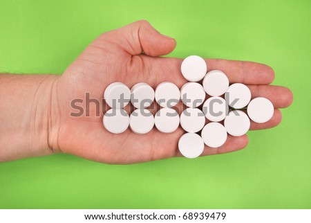 The arrow is combined from white tablets. The arrow lays on a hand. On a green background.