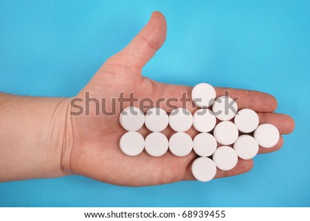 The arrow is combined from white tablets. The arrow lays on a hand. On a blue background.