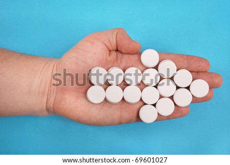 The arrow is combined from white tablets. The arrow lays on a hand. On a blue background.