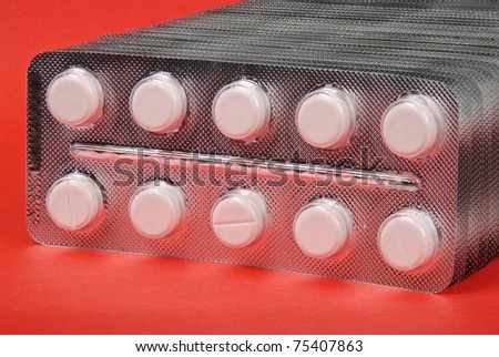 Plenty of white tablets in packing. Silver packs pills. Pills on red background