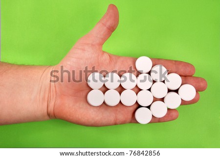 The arrow is combined from white tablets. The arrow lays on a hand. On a green background.
