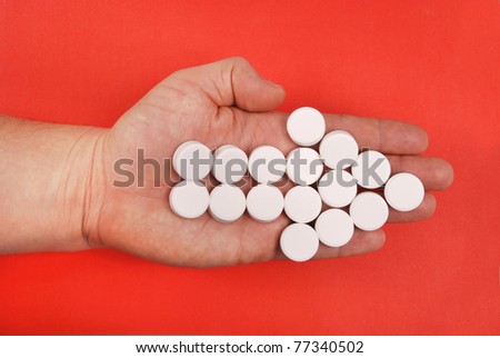 The arrow is combined from white tablets. The arrow lays on a hand. On a red background.