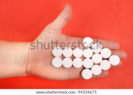 The arrow is combined from white tablets. The arrow lays on a hand. On a red background.