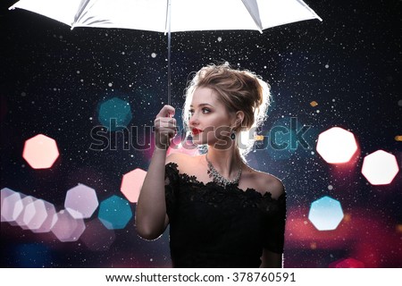Beautiful woman  with  white umbrella in flash lights and rain drops