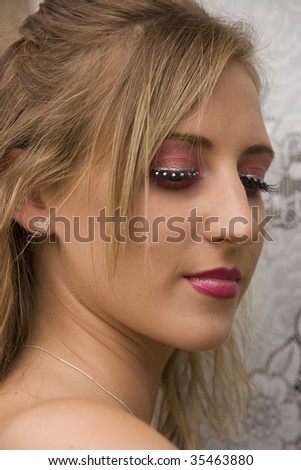 Head shot of pretty teenage girl wearing heavy pink make up looking down.
