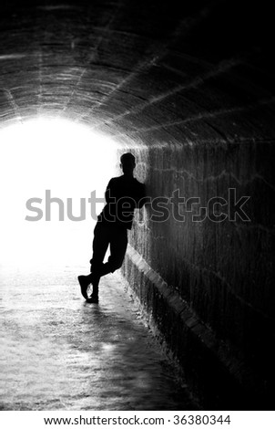 Aloneness. Human silhouette in back lighting in tunnel exit (shallow DOF)