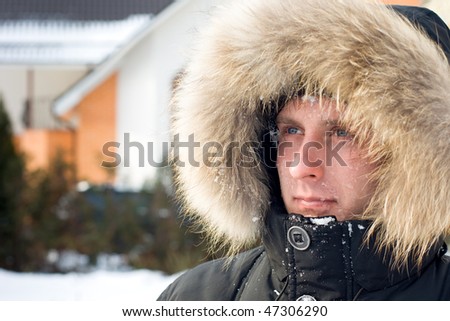 Snowball fight - man in warm jacket with furry hood in the yard