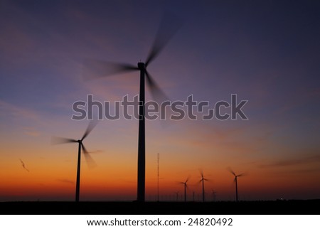 The sun rises above spinning turbines generating electrical power.