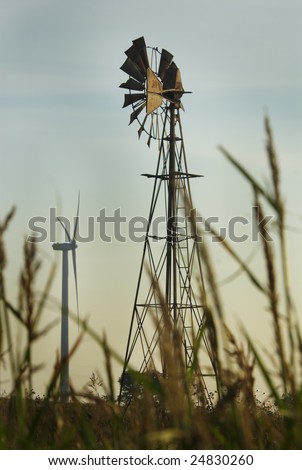 Old and new technologies stand in contrast as a farm windmill rises above a farm field and a wind turbine stands nearby.