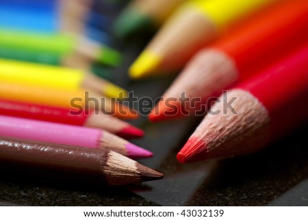 A small set of colored pencils faces a larger set, shallow depth of field.