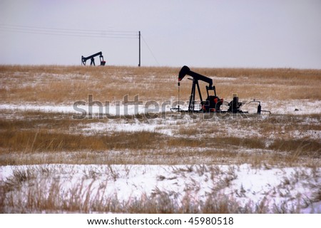 Oil rigs operate in a wintry rural landscape.