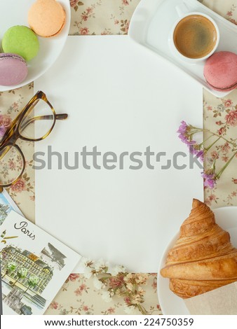 Blank sheet of paper for notes on a flower tablecloth with coffee, macaroon, croissants and postcards in the French style