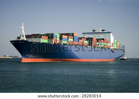 A large, ocean going container vessel and tug boat entering the main channel in the harbor.