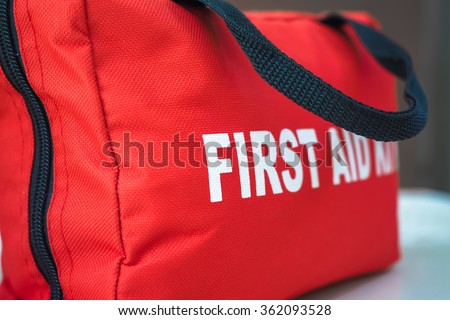 First Aid Kit\
A red first aid kit bag with a black zip and handle, in closeup.