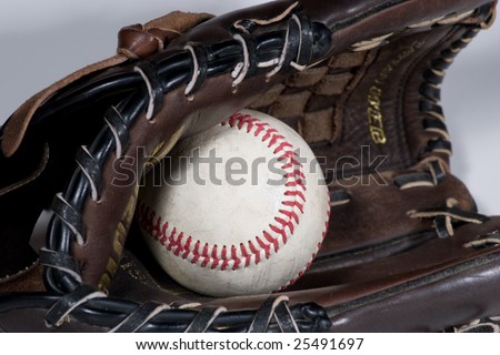 Brown leather baseball glove with baseball inside on a grey background for easy isolation