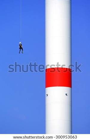 One Worker to let oneself down on a rope at a extreme high wind generator.