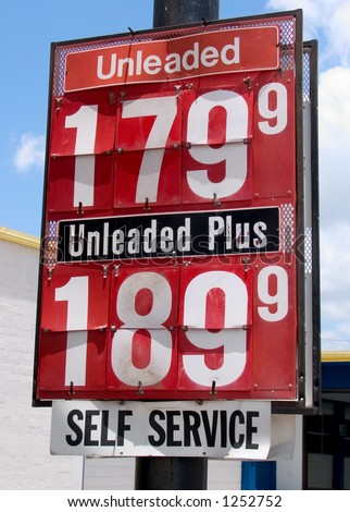 Old beat up gas price sign outside a run down service station.